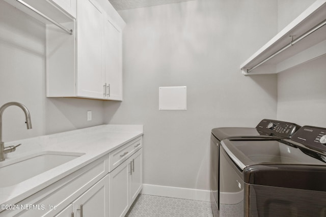 clothes washing area with sink, separate washer and dryer, cabinets, and light tile floors