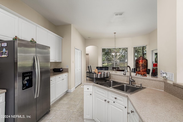 kitchen featuring white cabinetry, stainless steel fridge with ice dispenser, sink, and hanging light fixtures