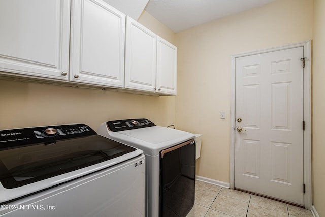 laundry area with separate washer and dryer, light tile patterned floors, and cabinets