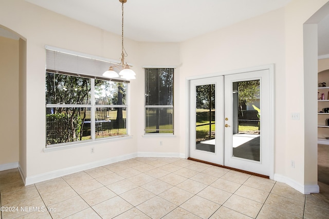 unfurnished dining area featuring french doors, light tile patterned floors, and a notable chandelier