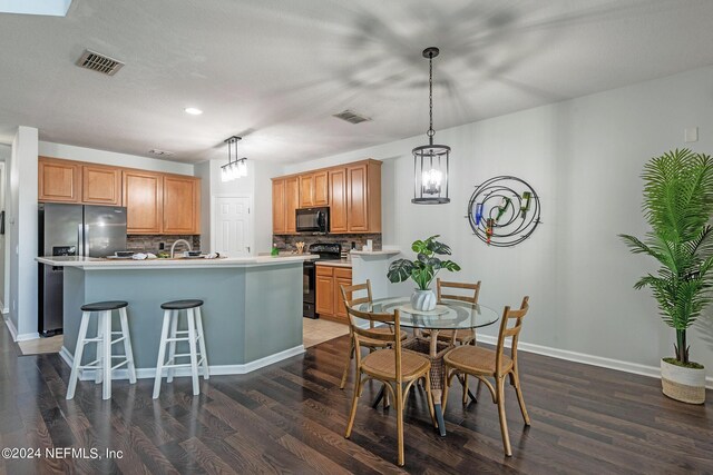 kitchen featuring backsplash, dark hardwood / wood-style floors, a kitchen island with sink, and black appliances