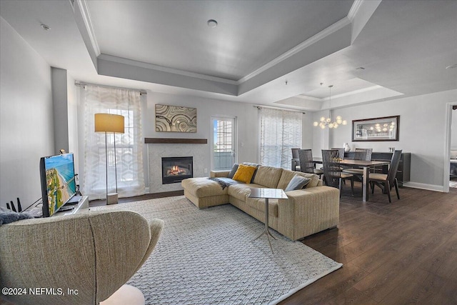 living room featuring a notable chandelier, dark hardwood / wood-style floors, a raised ceiling, and crown molding