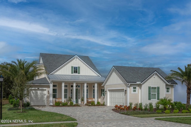 modern farmhouse style home with metal roof, decorative driveway, board and batten siding, and an attached garage