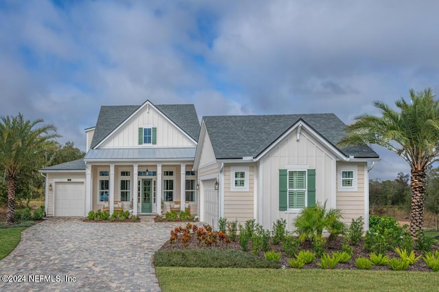 view of front of house with a shingled roof, metal roof, an attached garage, decorative driveway, and board and batten siding