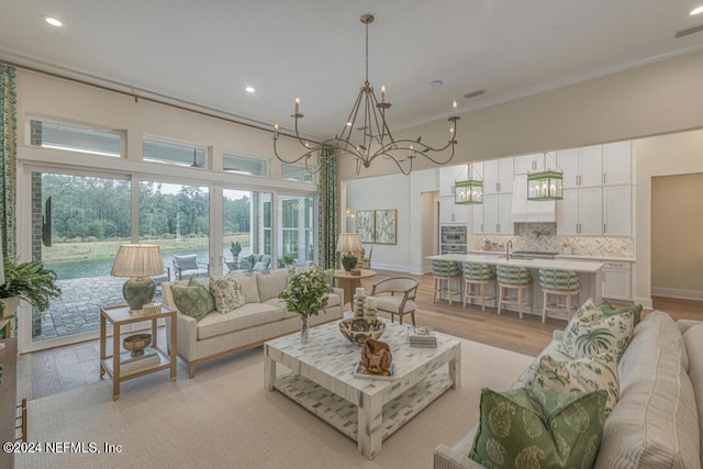 living room with light wood-style floors, a high ceiling, baseboards, and recessed lighting