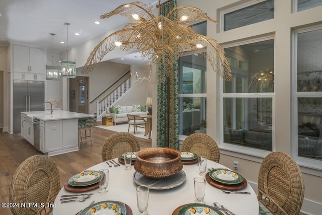 dining space featuring recessed lighting, stairway, a notable chandelier, and wood finished floors