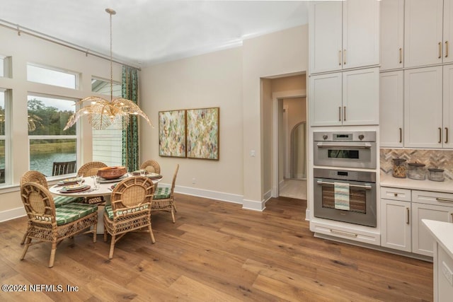 dining area with baseboards, a notable chandelier, and light wood finished floors