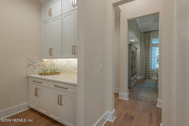 bar featuring baseboards, decorative backsplash, and dark wood-style flooring