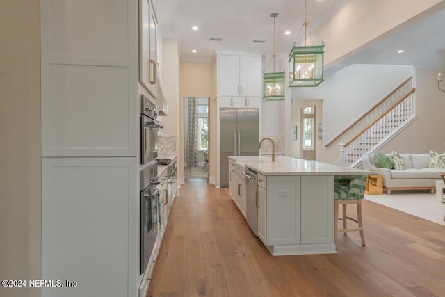 kitchen with appliances with stainless steel finishes, a breakfast bar, open floor plan, decorative light fixtures, and light wood-style floors