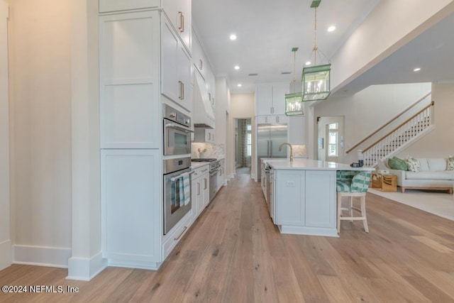 kitchen featuring light countertops, open floor plan, white cabinets, and light wood-style flooring