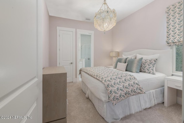 bedroom featuring a notable chandelier, connected bathroom, and light colored carpet