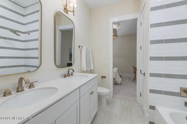 full bath featuring toilet, connected bathroom, double vanity, and a sink