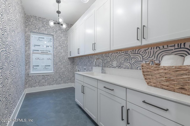 laundry area featuring a sink, baseboards, and wallpapered walls