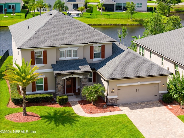 view of front of property with a water view, a garage, and a front lawn