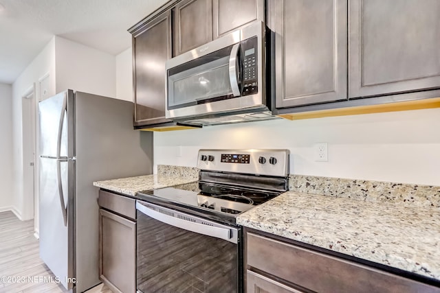 kitchen with light stone counters, light hardwood / wood-style flooring, and stainless steel appliances