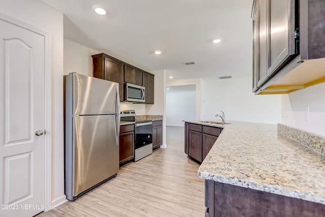 kitchen featuring sink, light hardwood / wood-style flooring, light stone countertops, dark brown cabinetry, and stainless steel appliances