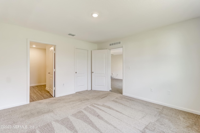 unfurnished bedroom featuring light colored carpet and a closet