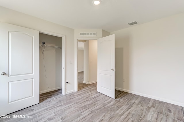 unfurnished bedroom with a closet and light wood-type flooring