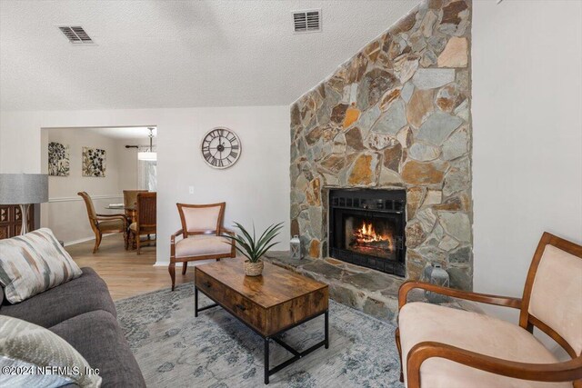 living room with wood-type flooring, lofted ceiling, a textured ceiling, and a fireplace