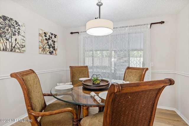 dining area with light hardwood / wood-style flooring and a textured ceiling