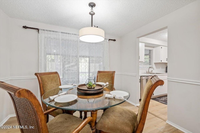 dining area featuring sink, light hardwood / wood-style flooring, and a textured ceiling