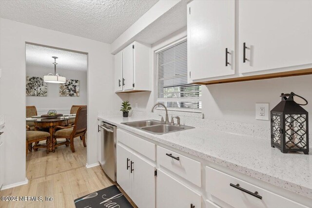 kitchen featuring light hardwood / wood-style flooring, dishwasher, pendant lighting, sink, and white cabinets