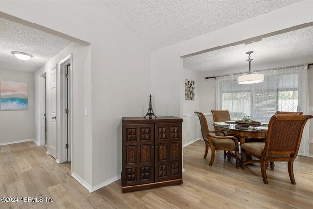 dining space with light hardwood / wood-style floors and a textured ceiling