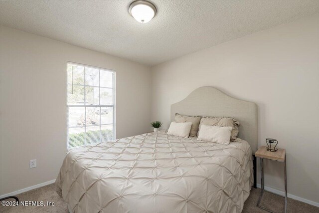 carpeted bedroom featuring a textured ceiling and multiple windows