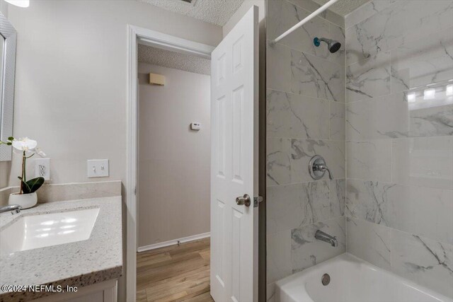 bathroom with tiled shower / bath, a textured ceiling, vanity, and wood-type flooring