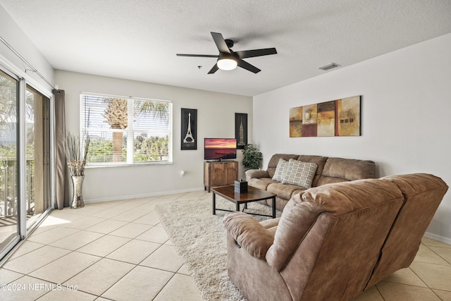 living room featuring ceiling fan, light tile patterned flooring, and a textured ceiling