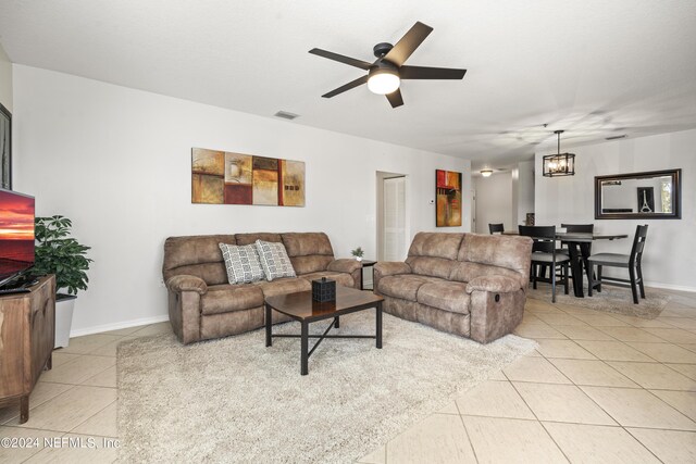 tiled living room featuring ceiling fan with notable chandelier