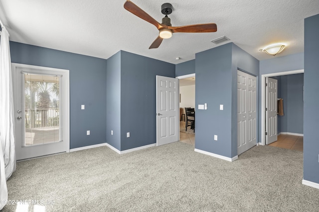 unfurnished bedroom featuring light carpet, a textured ceiling, and ceiling fan