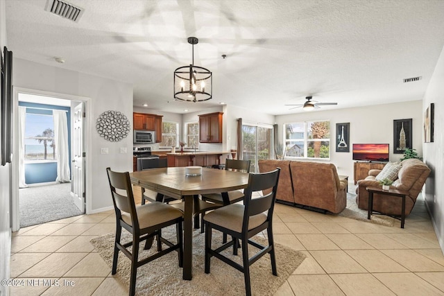 dining area with ceiling fan with notable chandelier, a healthy amount of sunlight, and light tile patterned flooring