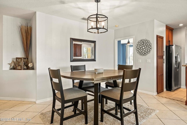 tiled dining space with ceiling fan with notable chandelier and a textured ceiling