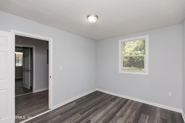 unfurnished room with a textured ceiling and dark hardwood / wood-style floors