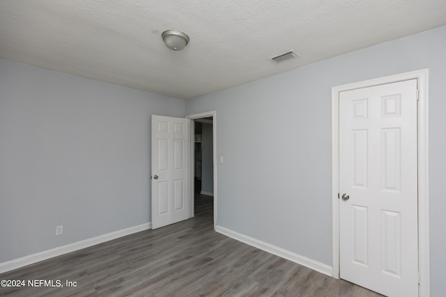 unfurnished room with a textured ceiling and dark hardwood / wood-style floors