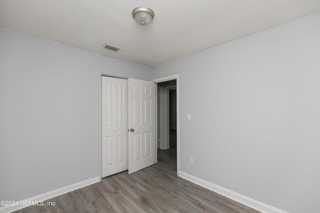 unfurnished bedroom featuring hardwood / wood-style floors, a textured ceiling, and a closet