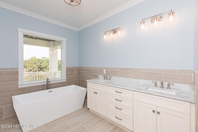 bathroom featuring a freestanding tub, crown molding, tile walls, and a sink