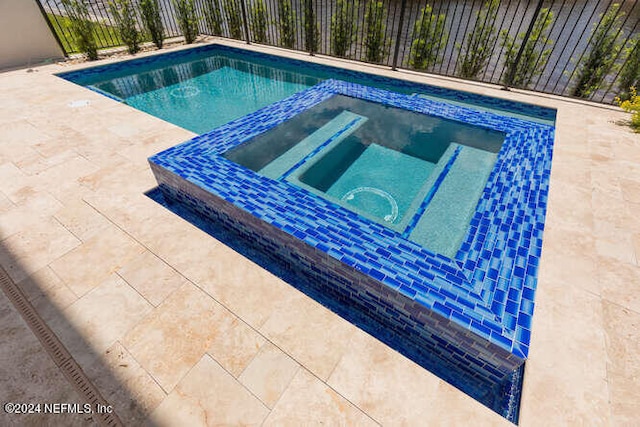 view of pool with an in ground hot tub, a patio, fence, and a fenced in pool