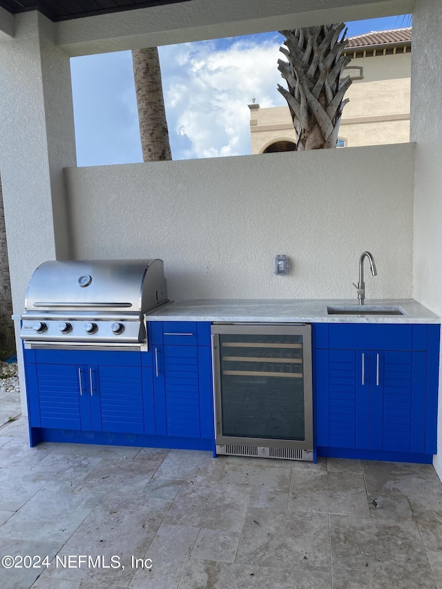 view of patio featuring wine cooler, a sink, an outdoor kitchen, and area for grilling