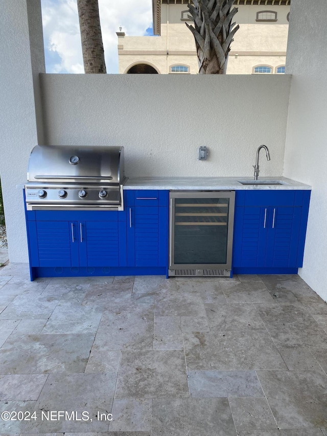 view of patio / terrace with area for grilling, a garage, a sink, exterior kitchen, and beverage cooler