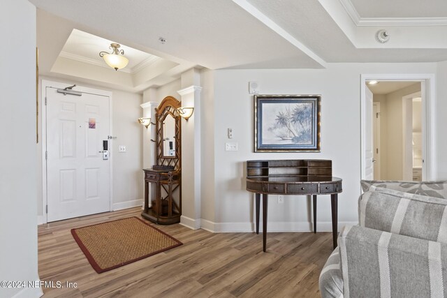 entrance foyer with a tray ceiling, wood-type flooring, and ornamental molding