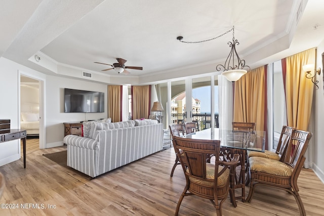 living room with a tray ceiling, light hardwood / wood-style flooring, and ornamental molding