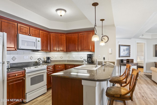 kitchen with pendant lighting, sink, white appliances, tasteful backsplash, and kitchen peninsula