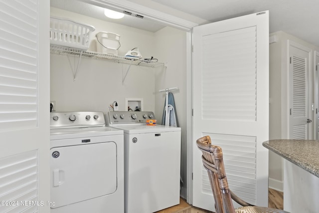 laundry area with washing machine and dryer and light hardwood / wood-style floors