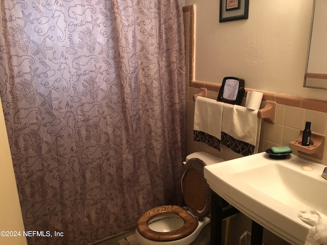 bathroom featuring walk in shower, tile walls, toilet, and sink