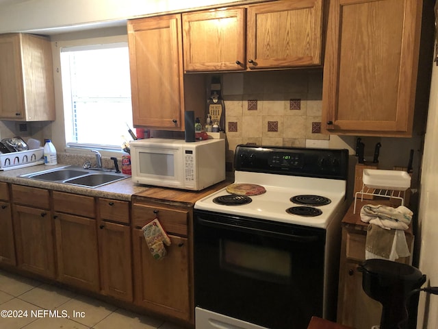 kitchen with decorative backsplash, white appliances, light tile patterned flooring, and sink