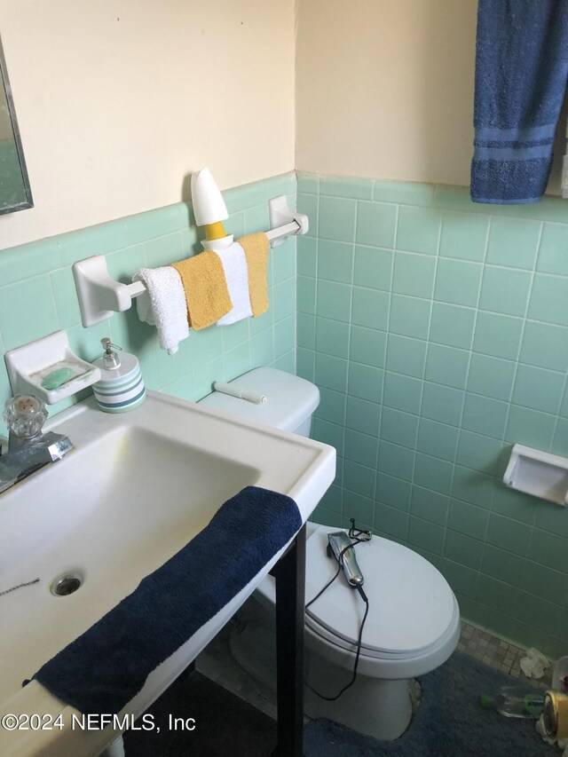 bathroom featuring tile walls and toilet