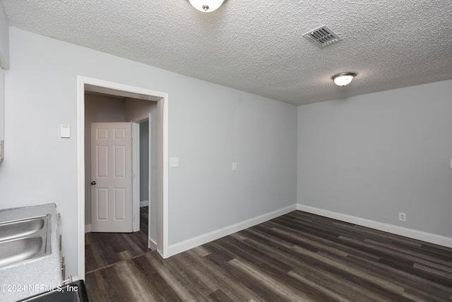 unfurnished room featuring dark wood-type flooring, sink, and a textured ceiling