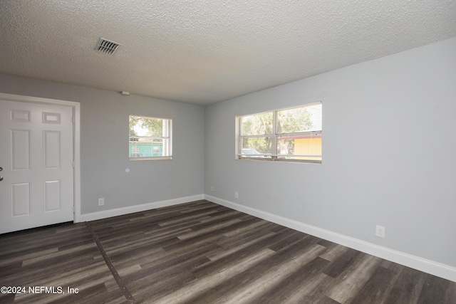 spare room with dark hardwood / wood-style floors and a textured ceiling